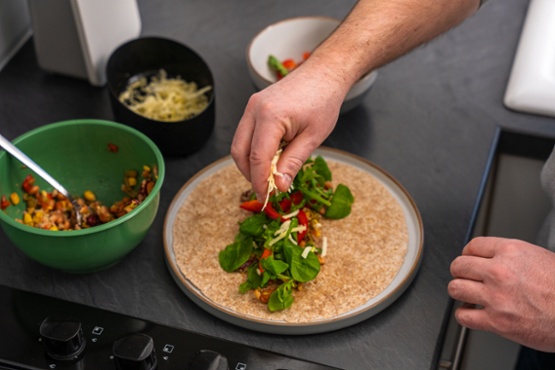 A person making a salad wrap