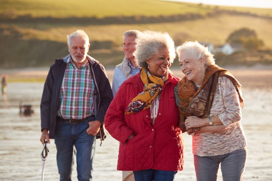 Four older friends walking along beach