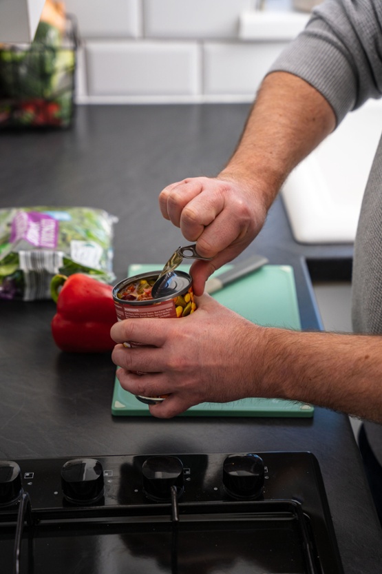 A man opening a tin of vegetables