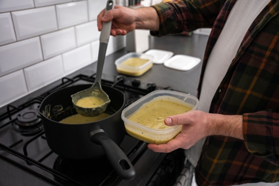 Someone putting soup into a container