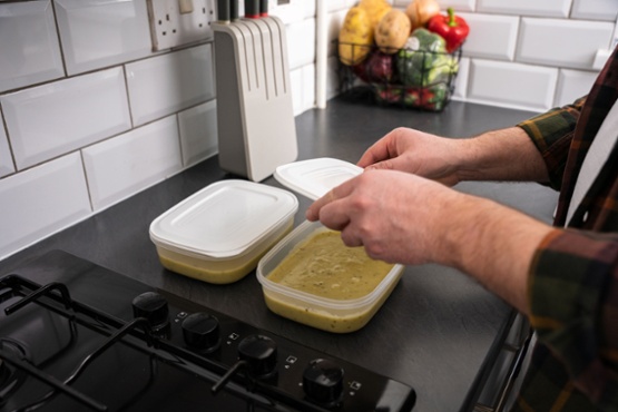 A man putting a lid on a container of soup